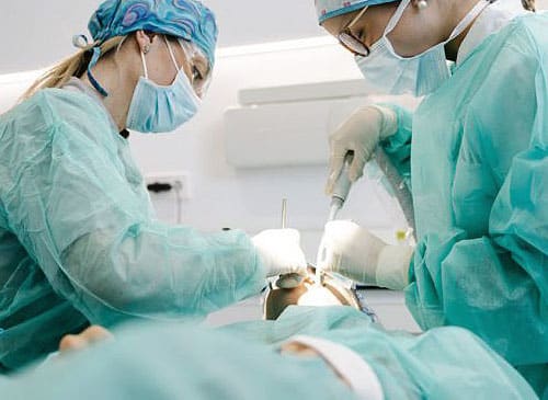 Doctors are doing oral surgery of a patient.